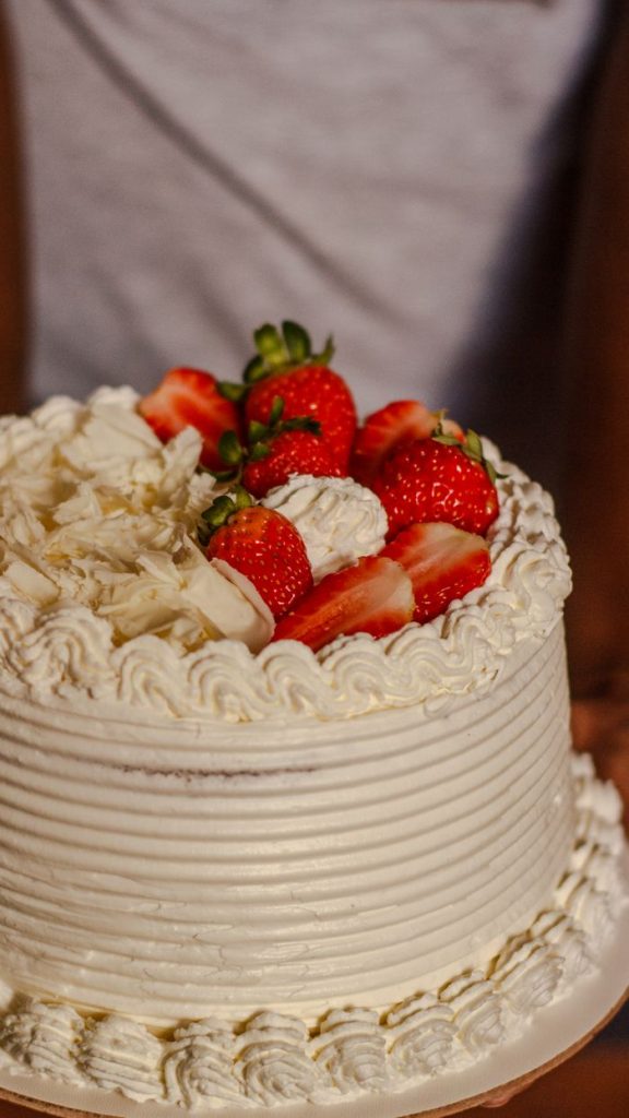 Mouth-watering layer cake topped with fresh strawberries and whipped cream.