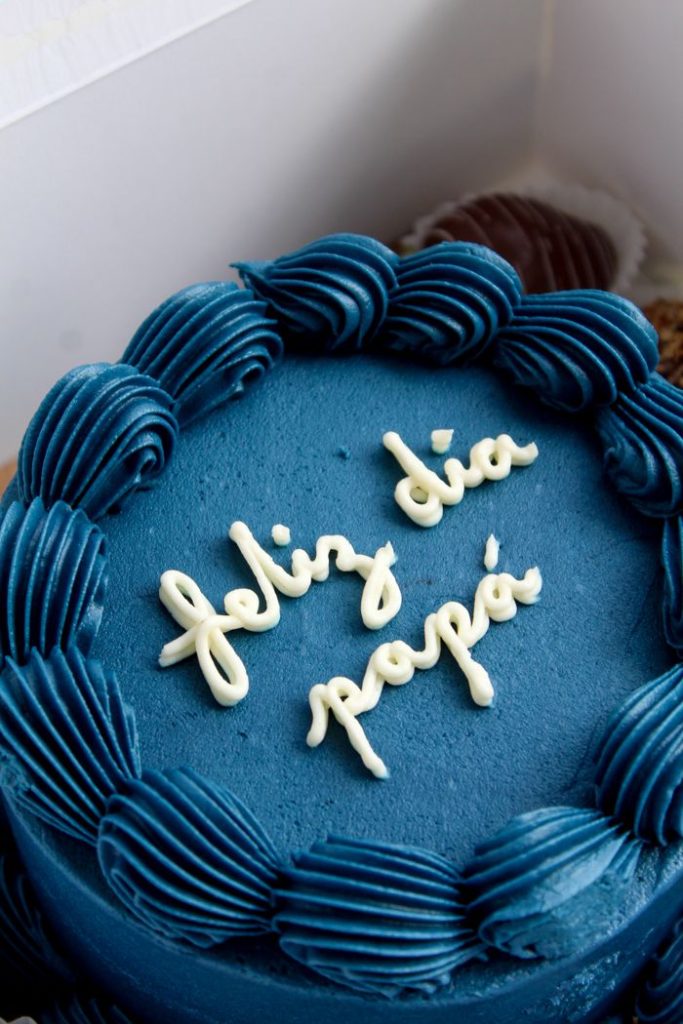 Celebrate Father's Day with a vibrant blue cake adorned with 'Feliz Día Papá' frosting, perfect for any dad.
