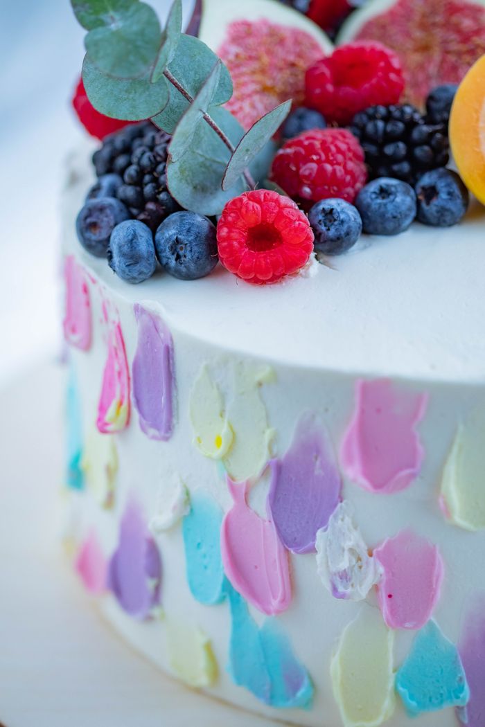 Close-up of a vibrant cake topped with fresh berries and colorful icing details.